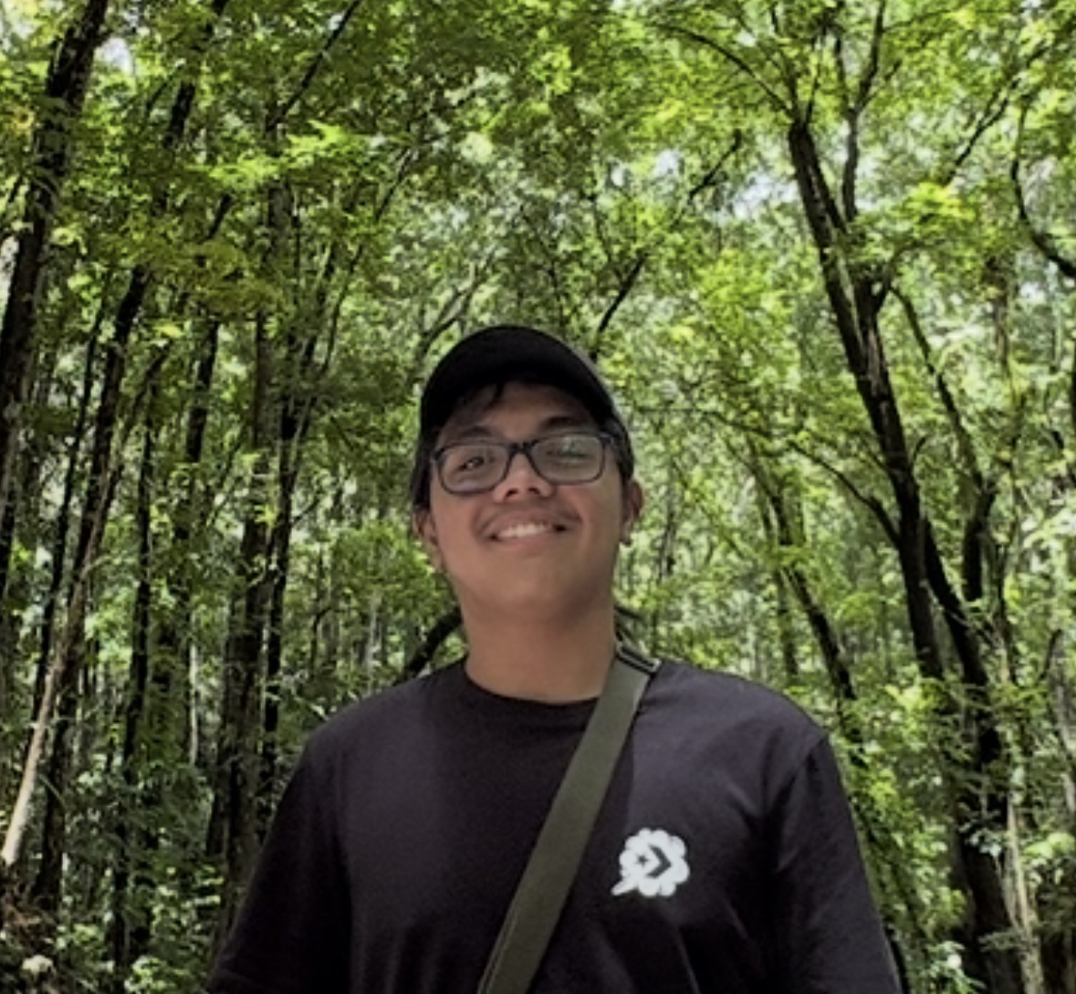 Elijah wearing glasses and a dark cap outdoors